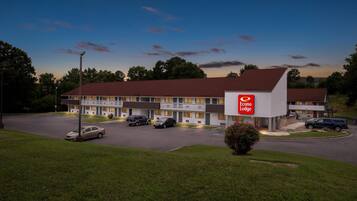 Un motel con un llamativo letrero de Econo Lodge, varios espacios de estacionamiento y un césped bien cuidado.