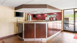A reception area with a wooden counter, a flat-screen TV mounted on the wall, and a large window providing a view of the outdoors. - Econo Lodge Hickory (Hickory)