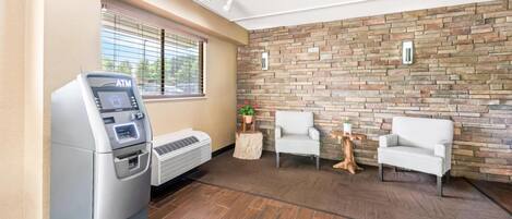 A modern lobby with an ATM, seating area, and a stone wall.