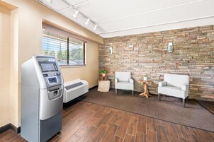 A modern lobby with an ATM, seating area, and a stone wall.