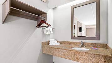 A bathroom with a granite countertop sink, a mirror, a wooden medicine cabinet, and a towel rack.