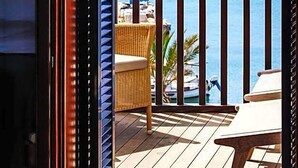 A balcony with a view of a body of water, a chair, and a table. - Portixol Hotel & Restaurant (Palma de Mallorca)