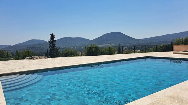 A rectangular swimming pool with clear blue water, surrounded by a tiled deck.