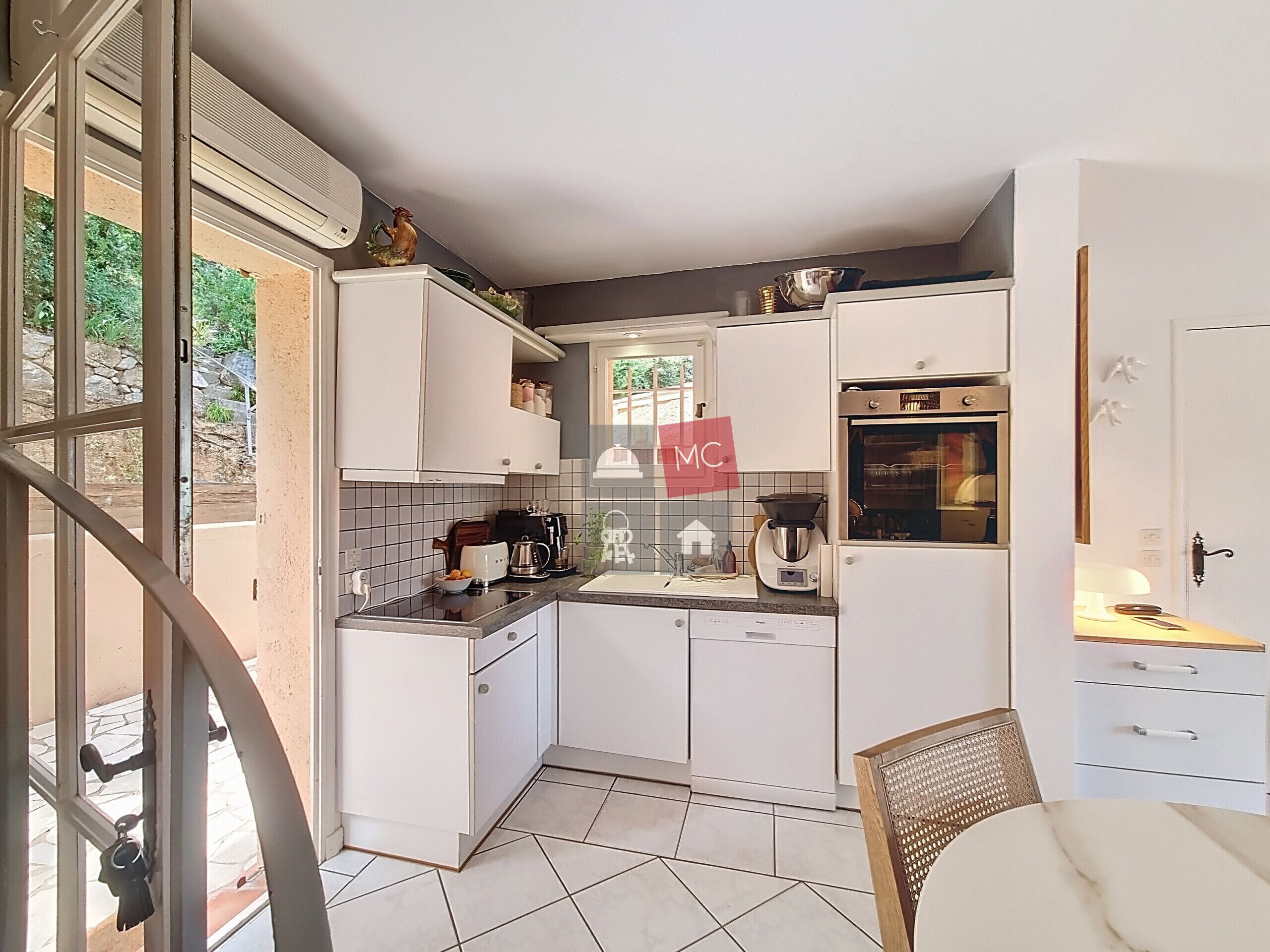 Una cocina compacta con armarios blancos, cafetera y tostadora.