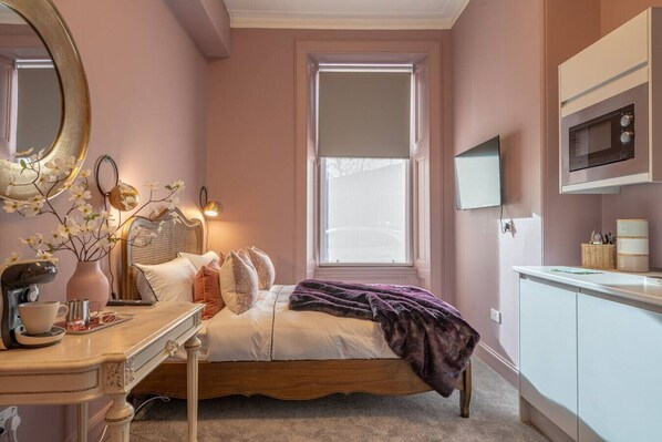 A bedroom with a bed, bedside table, lamp, and a window.