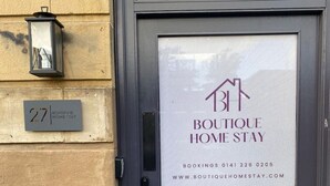 A dark-colored door with a sign for Boutique Home Stay, including a contact number and website. - B HOME STAY Blossom Lux Studio, Glasgow /  Airport (Paisley)