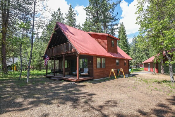 Une cabane dotée d’un porche, d’une terrasse et d’un petit espace extérieur aménagé pour s’asseoir.