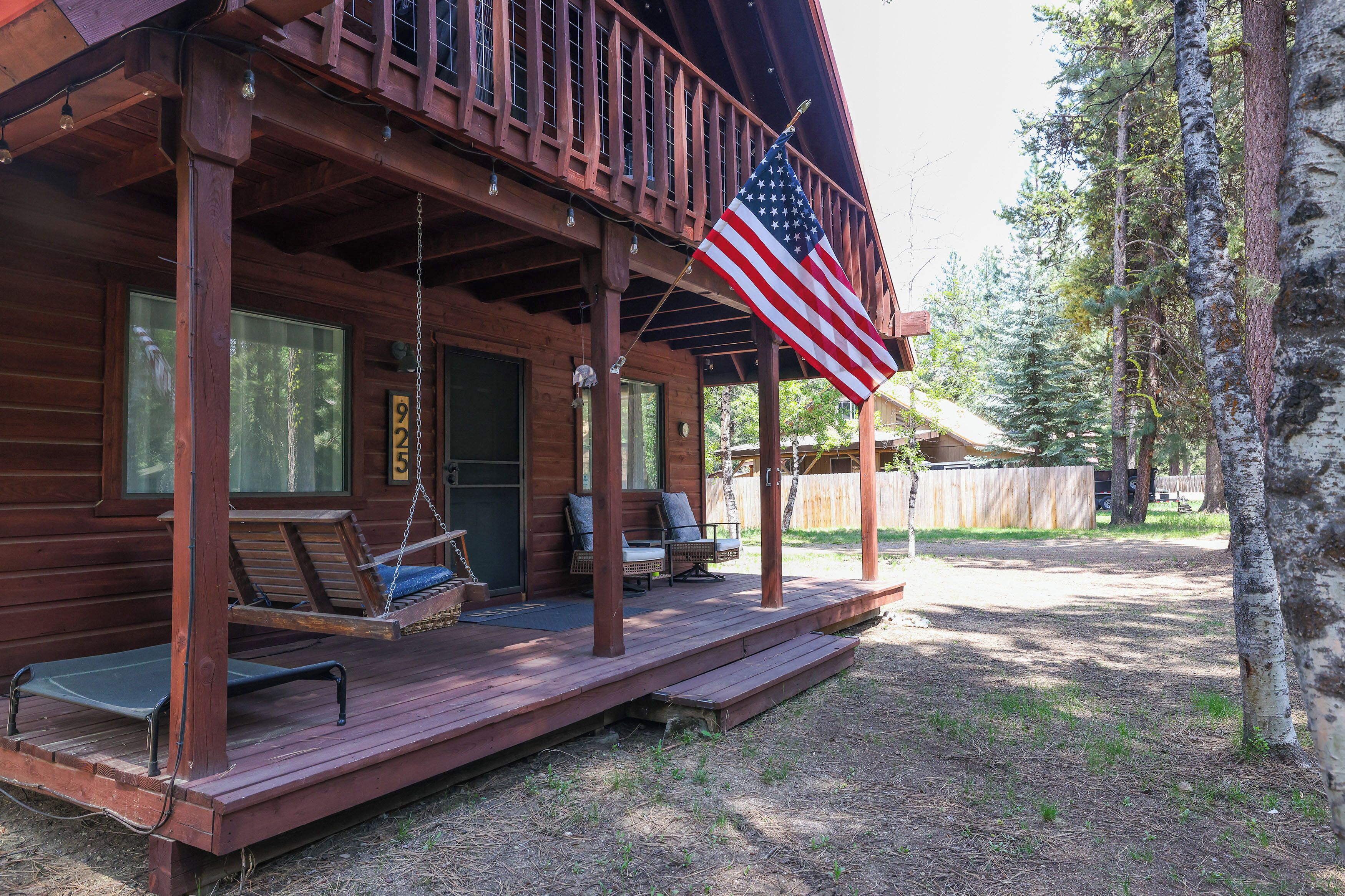 Una baita di legno con veranda, una sedia a dondolo e una bandiera americana.