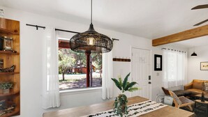 Un comedor con una mesa de madera, una lámpara colgante y vistas al exterior.