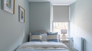Une chambre à coucher avec un lit, une table de chevet, une lampe et un radiateur.