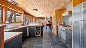 A modern kitchen with wooden cabinetry, a central island, and a built-in wine rack. - The Last Straw in Katoomba (Katoomba)