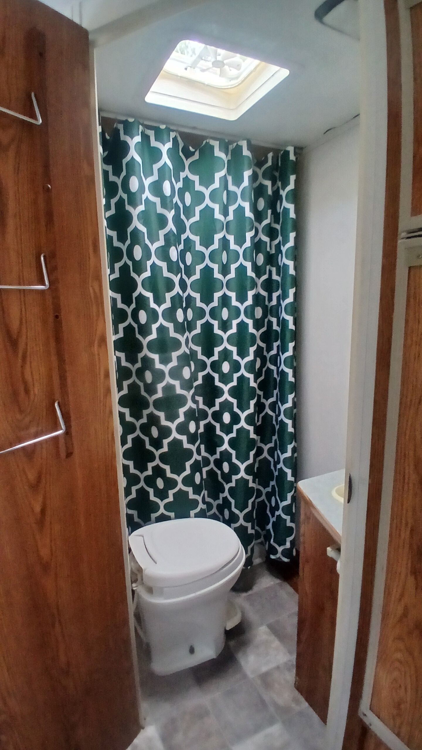 Baño pequeño con inodoro, cortina de ducha estampada y tragaluz.