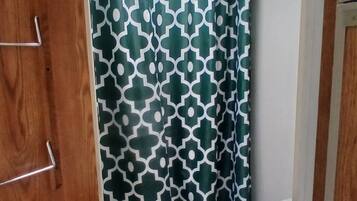 Baño pequeño con inodoro, cortina de ducha estampada y tragaluz.