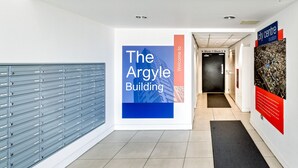 Un couloir avec un meuble de rangement bleu, une enseigne indiquant « The Argyle Building » et une autre indiquant « emplacement en centre-ville ».