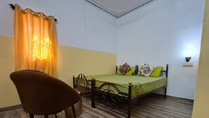 A small, neatly arranged bedroom with a single bed, a chair, and a bedside table. - Hype Hostel Udaipur (Udaipur)