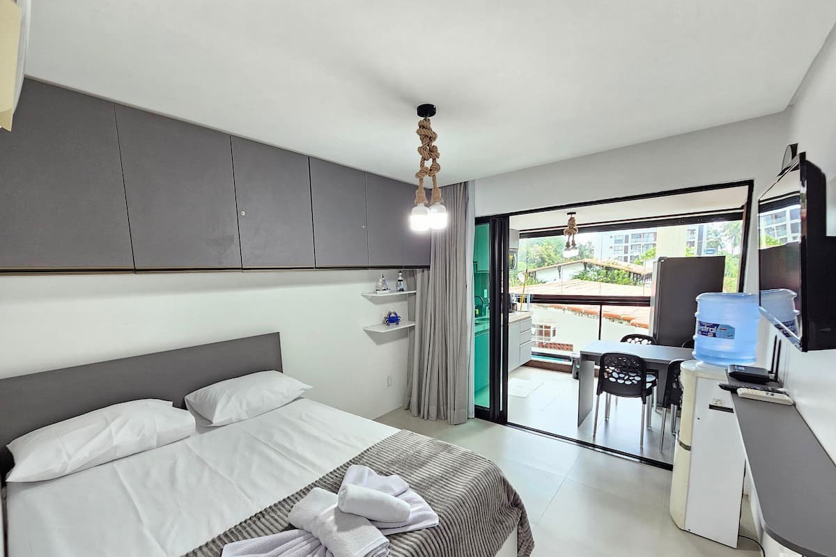 Ein Hotelzimmer mit Bett, Schreibtisch, Stuhl, Wasserspender und Blick ins Freie.