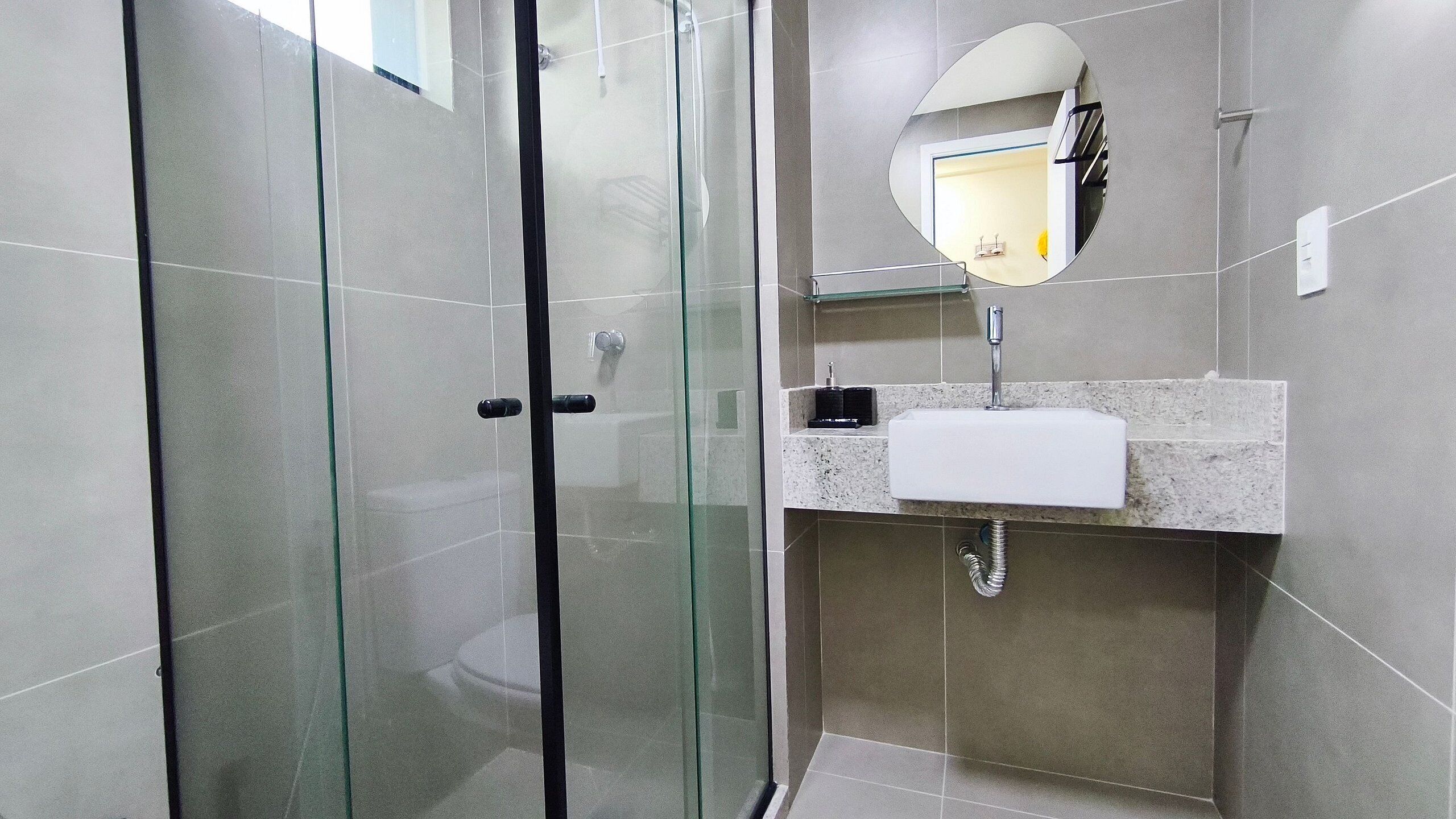 A modern bathroom with a glass-enclosed shower, a white sink, and a mirror.