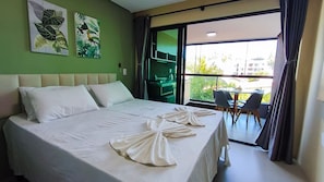 Hotelkamer met een bed, twee kussens, een handdoek, een groene muur en een balkon met stoelen.