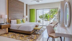 Une chambre d’hôtel moderne dotée d’un grand lit, d’un bureau, d’une chaise, d’un ventilateur de plafond et offrant une vue sur les palmiers à travers la porte vitrée.