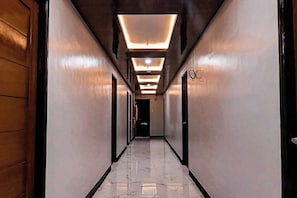 A long, narrow hallway with a polished marble floor, wooden doors on one side, and recessed lighting on the ceiling. - Gabz'k Hotel & Resort (Irosin)