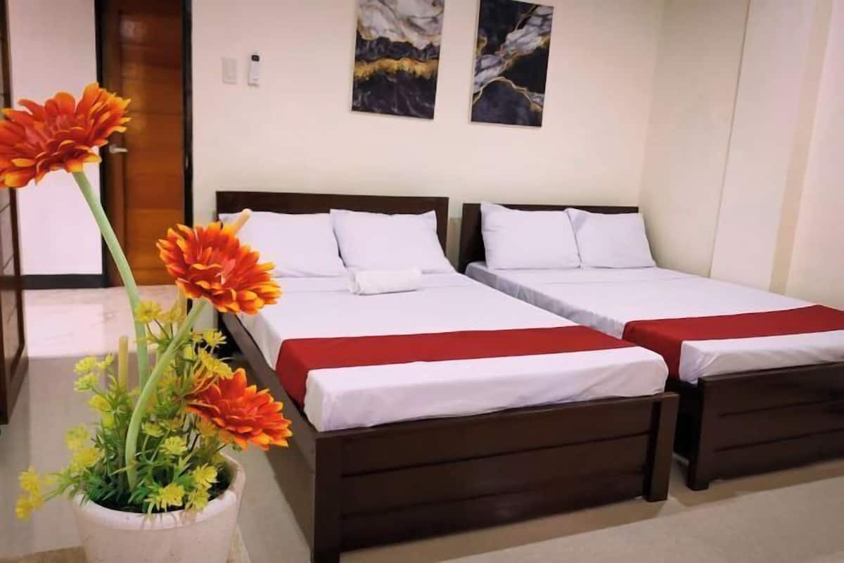 Una habitación de hotel con dos camas, una planta en maceta y obras de arte en la pared.