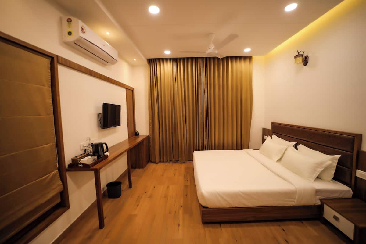 Una habitación de hotel con cama, televisión, escritorio y aire acondicionado.