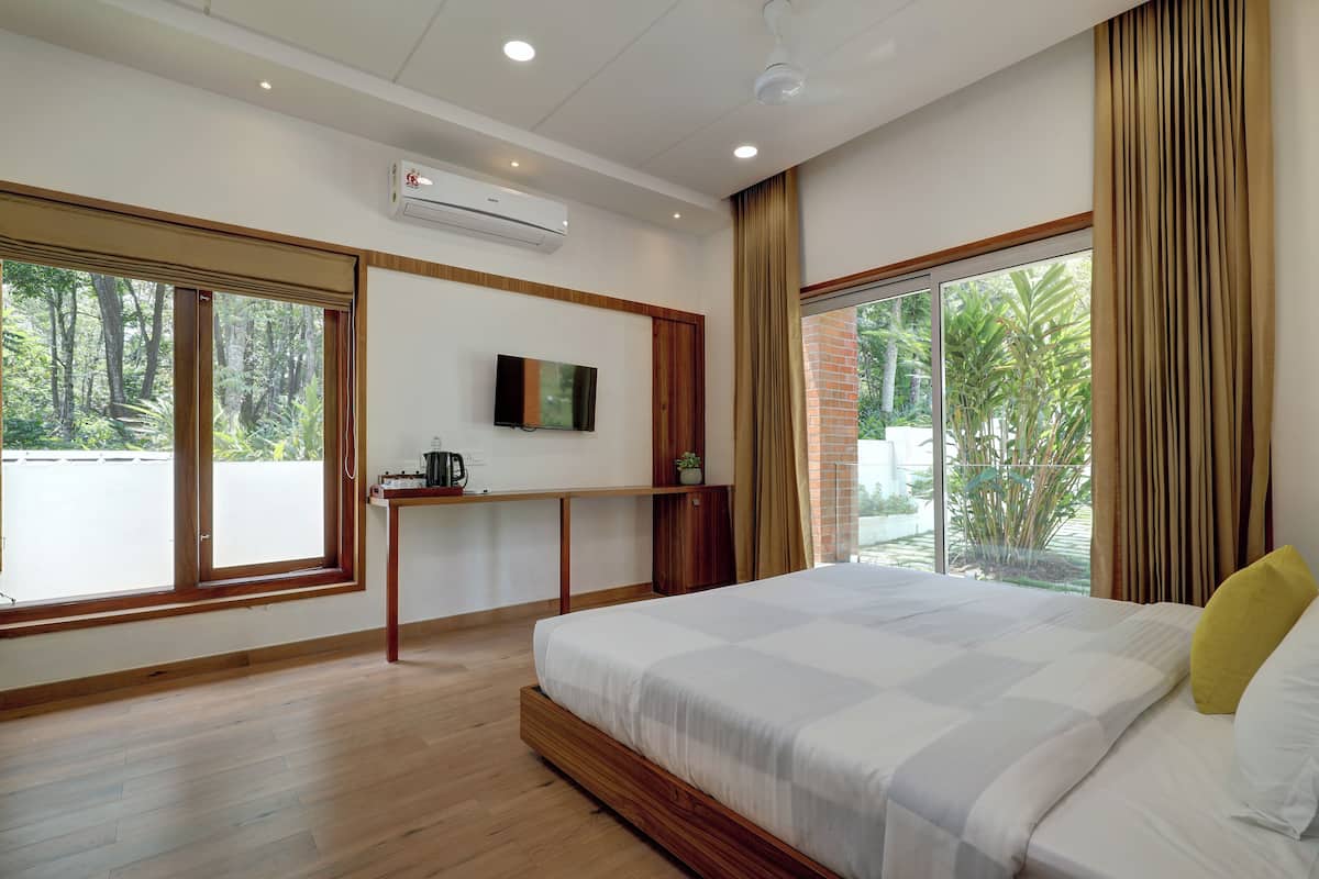 Habitación de hotel moderna con una cama grande, un televisor montado en la pared y una ventana con cortinas.