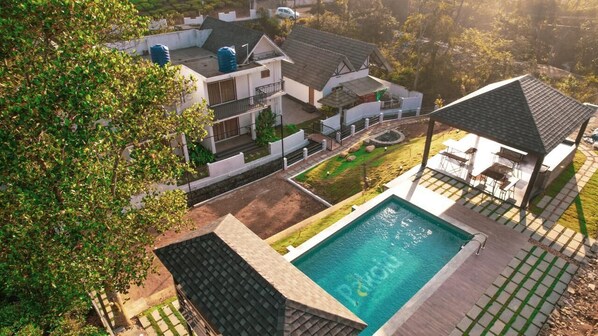 A residential area with a swimming pool, a covered patio, and a house with a balcony.