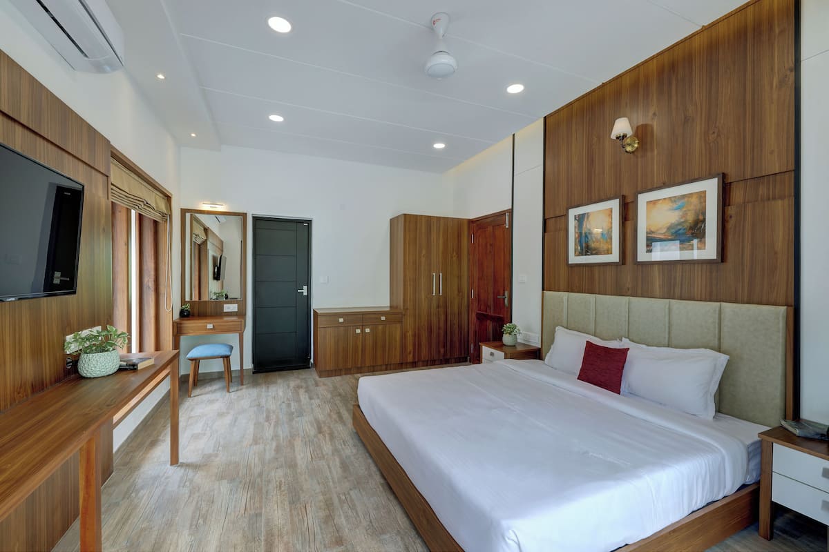 Un dormitorio moderno con una cama grande, un armario de madera, un escritorio con silla y un televisor de pantalla plana.