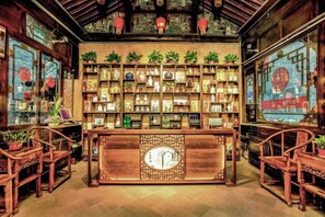 A traditional interior with wooden furniture, a central display case, and decorative plants.