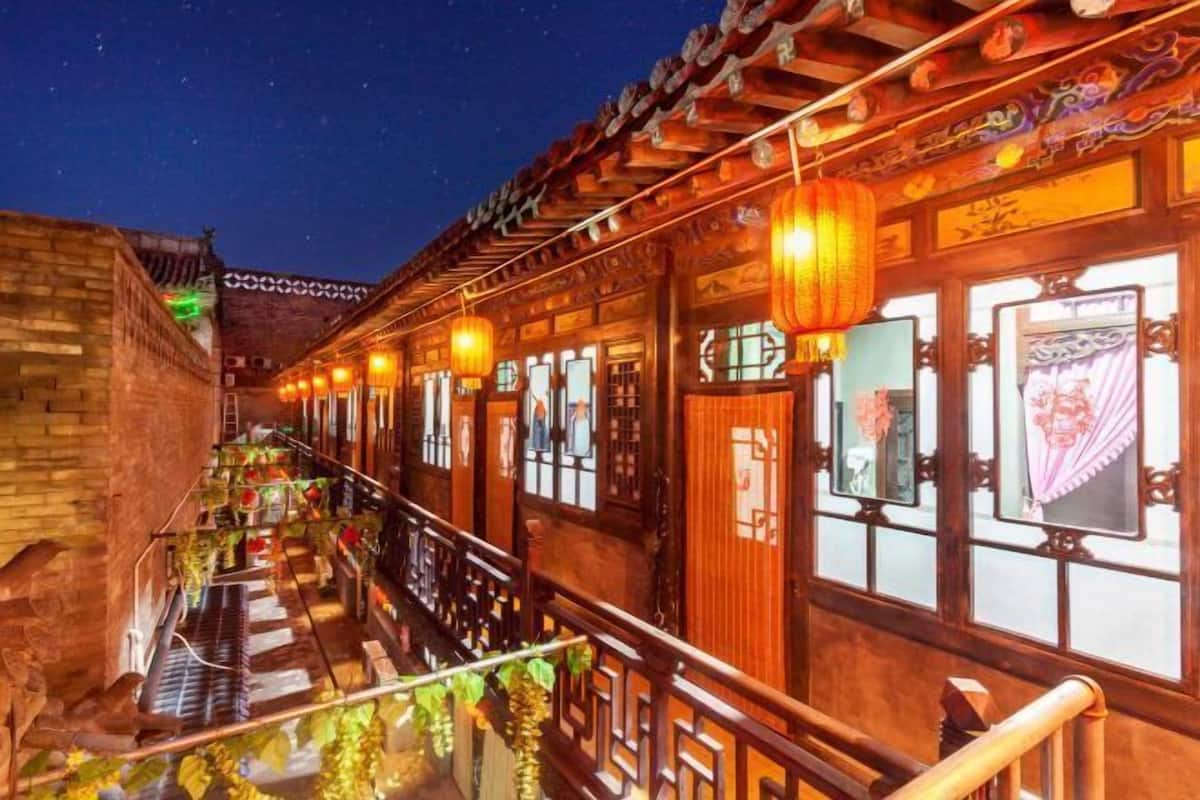 Un patio tradicional con edificios de madera, una escalera y faroles colgantes.