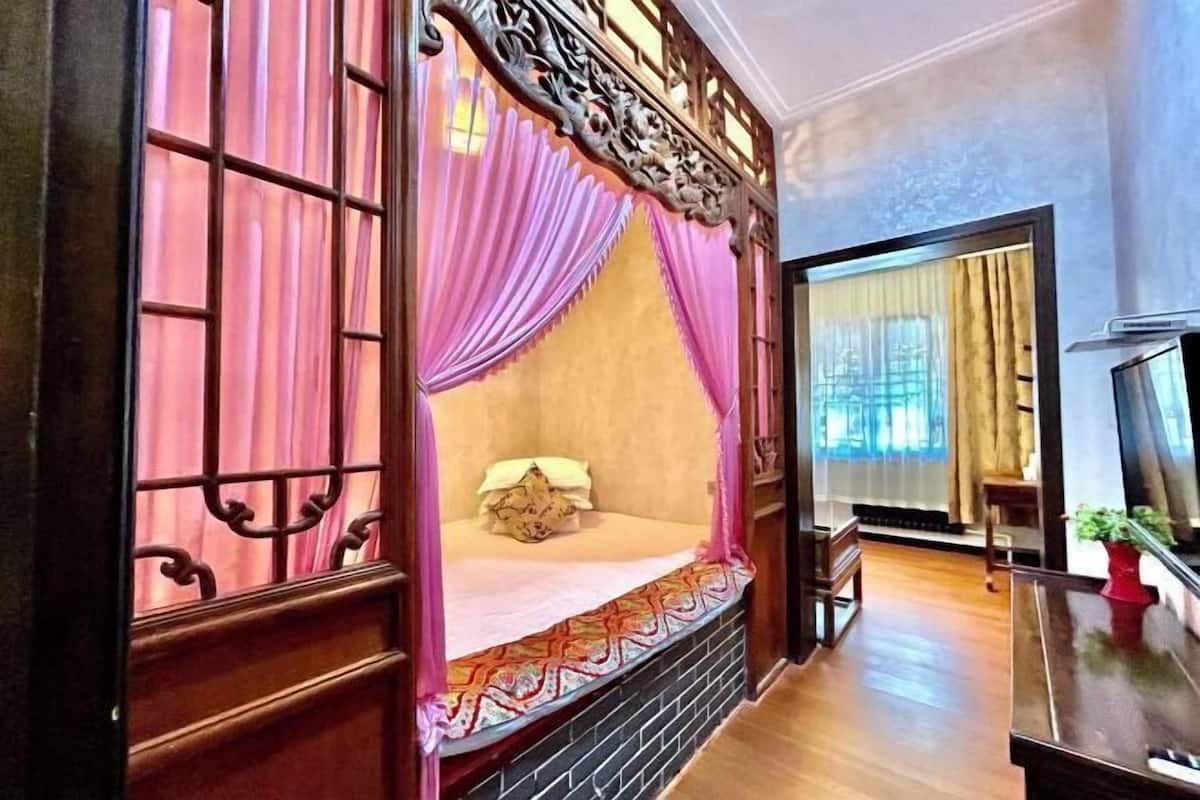 Una habitación tradicional con cama, cortinas y suelo de madera.