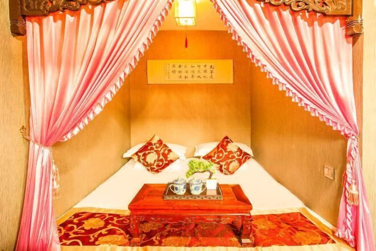 Una habitación tradicional con cama, almohadas, una bandeja con teteras y un cartel en la pared.