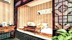 A traditional room with a bed, a wooden dresser, a desk, and a window with decorative iron bars. - Yongshengyuan Courtyard Retro Courtyard Inn (Pingyao Ancient City Branch) (Pingyao County)