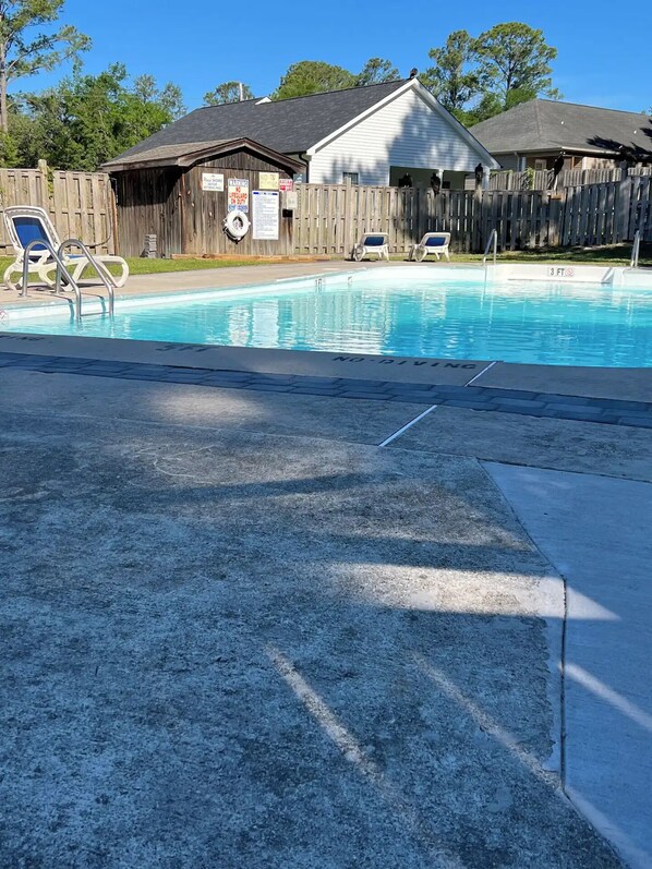 A swimming pool with a wooden fence, lounge chairs, and a lifeguard sign. - “Somewhere With You” (Calabash)