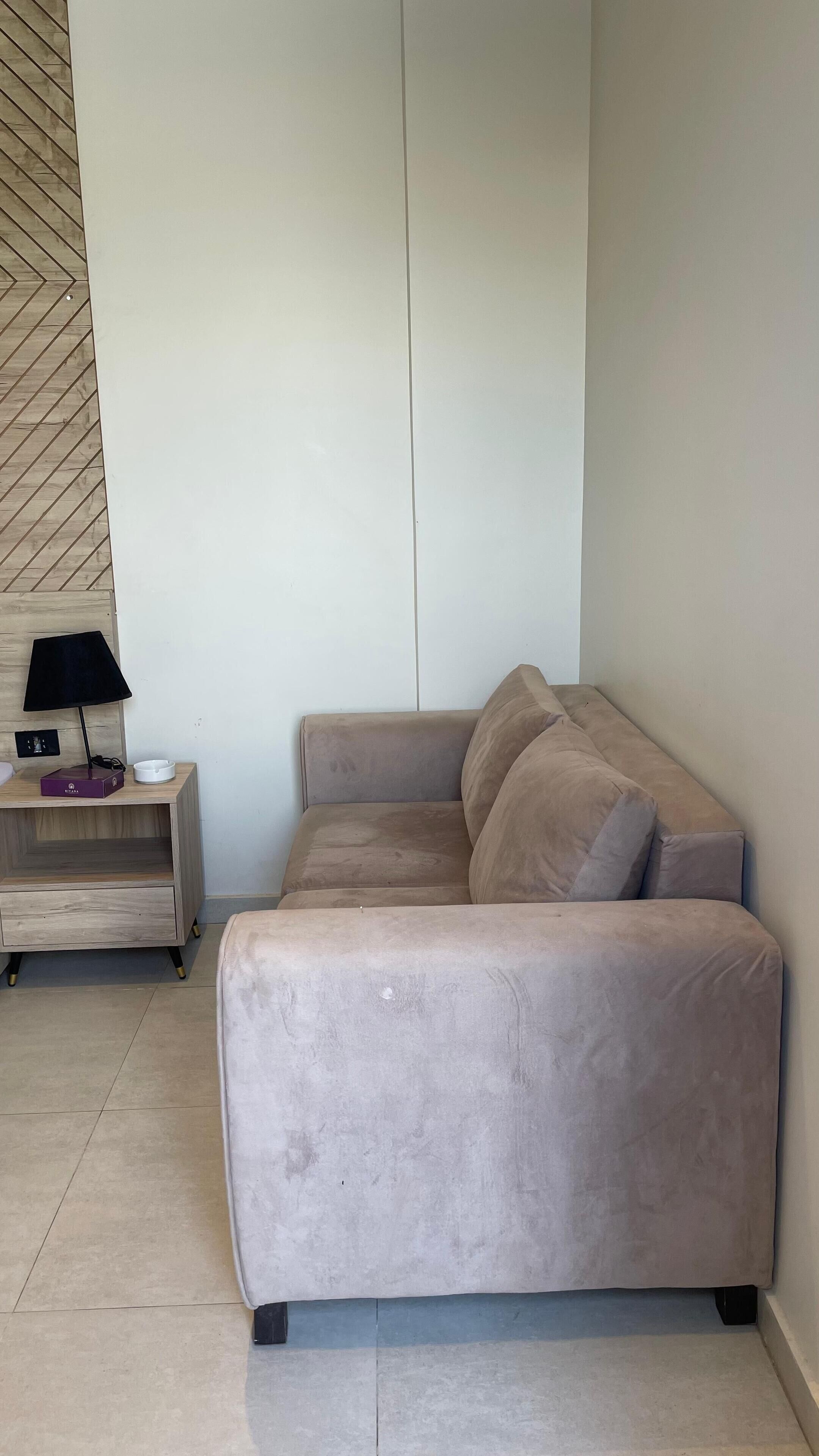A beige sofa in a room with a wooden floor and a wall with a herringbone pattern.
