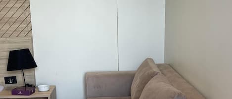 Un sofá color beige en una habitación con piso de madera y una pared con diseño de espiga.