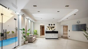A modern hotel lobby with a reception desk, a pool, and a large window. - Rivana Residence New Cairo - Pool & GYM Access (New Cairo)