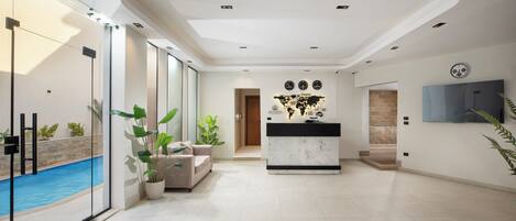A spacious living area with a pool, a reception desk, and a large wall map.
