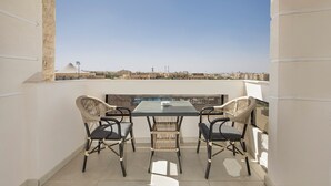 A balcony with a table and two chairs, overlooking a cityscape. - Rivana Residence New Cairo - Pool & GYM Access (New Cairo)