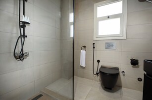 Un bagno moderno con cabina doccia in vetro, un water e una finestra che garantisce luce naturale.