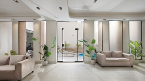 A modern living room with two sofas, a glass door leading to a pool area, and potted plants. - Rivana Residence New Cairo - Pool & GYM Access (New Cairo)