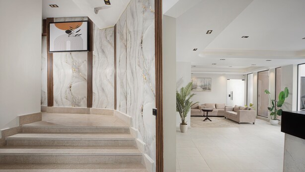 A modern interior with a marble staircase, a living area with sofas, and a large plant. - Rivana Residence New Cairo - Pool & GYM Access (New Cairo)
