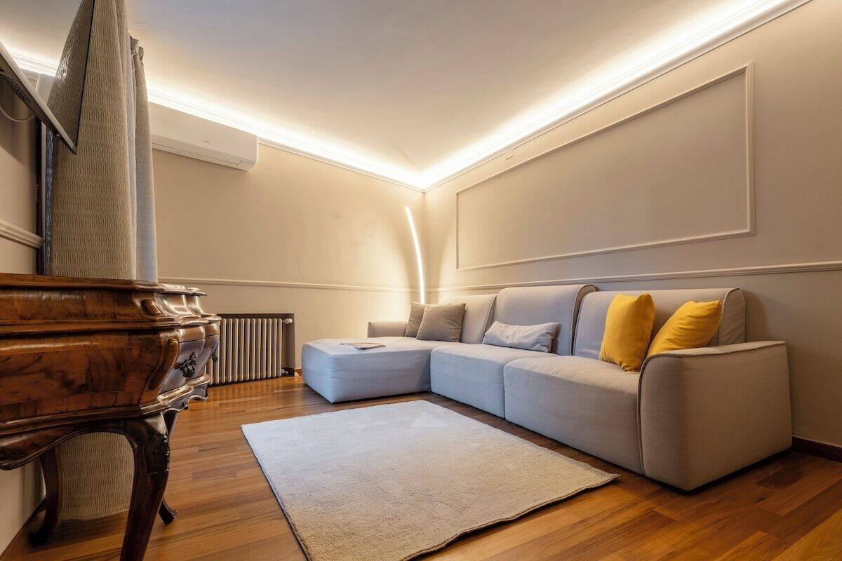 Un salon avec un canapé d’angle, un piano en bois et un radiateur.