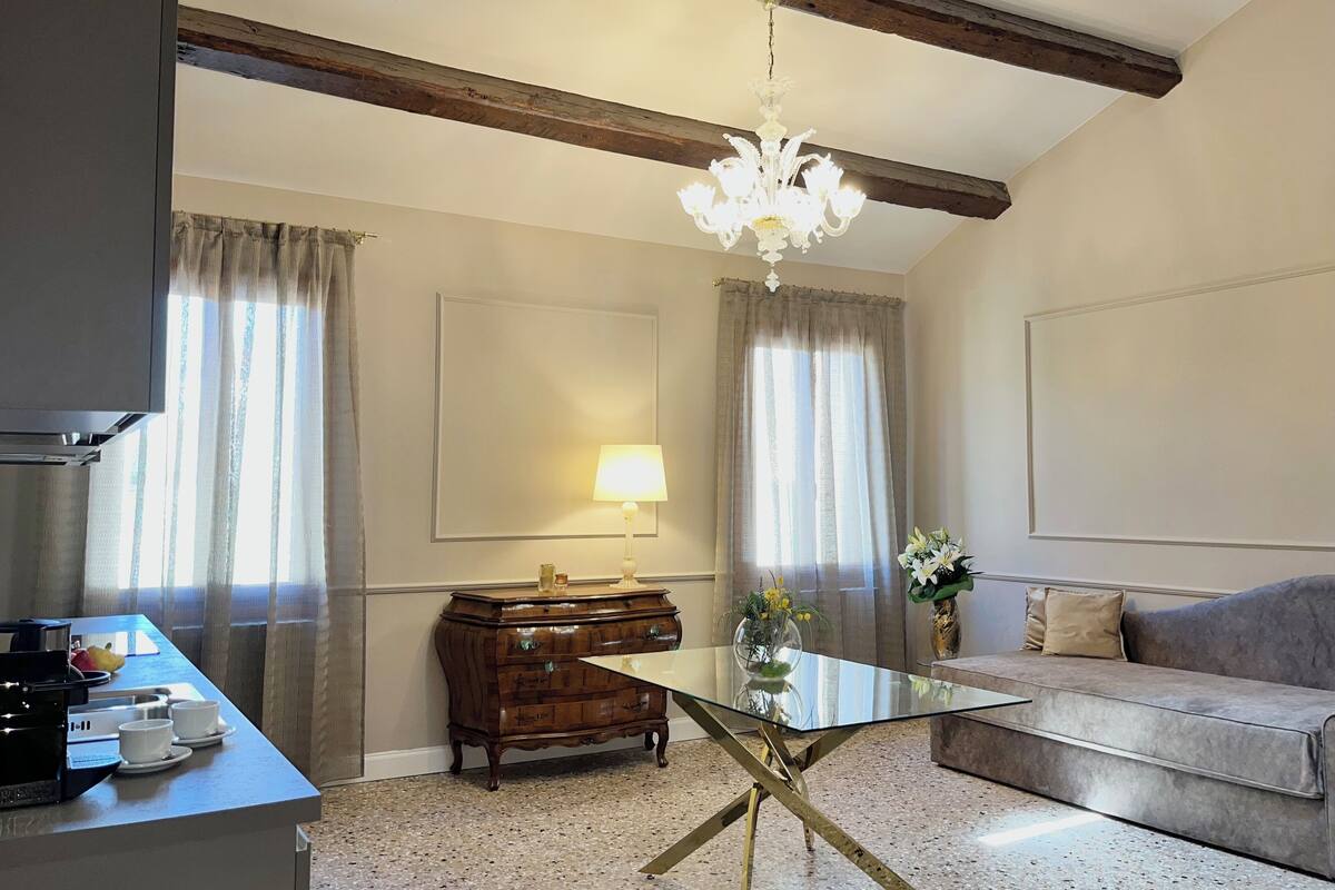Un salon avec une table basse en verre, un canapé, un meuble en bois et un lustre.