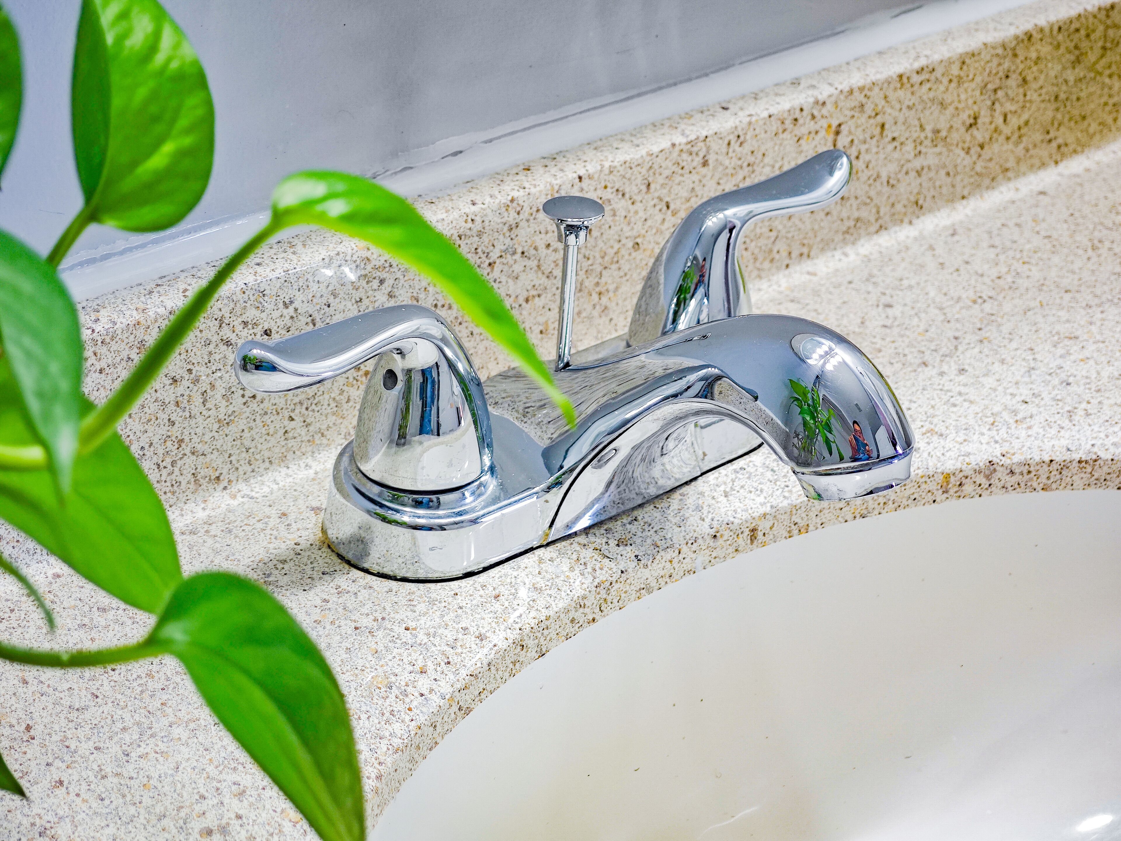 A bathroom sink with a chrome faucet and a speckled countertop.