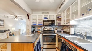 A modern kitchen with white cabinetry, a central island, stainless steel appliances, and a backsplash with blue tiles. - Walk to Beach + Restaurants: Ocean City Getaway (Ocean City)