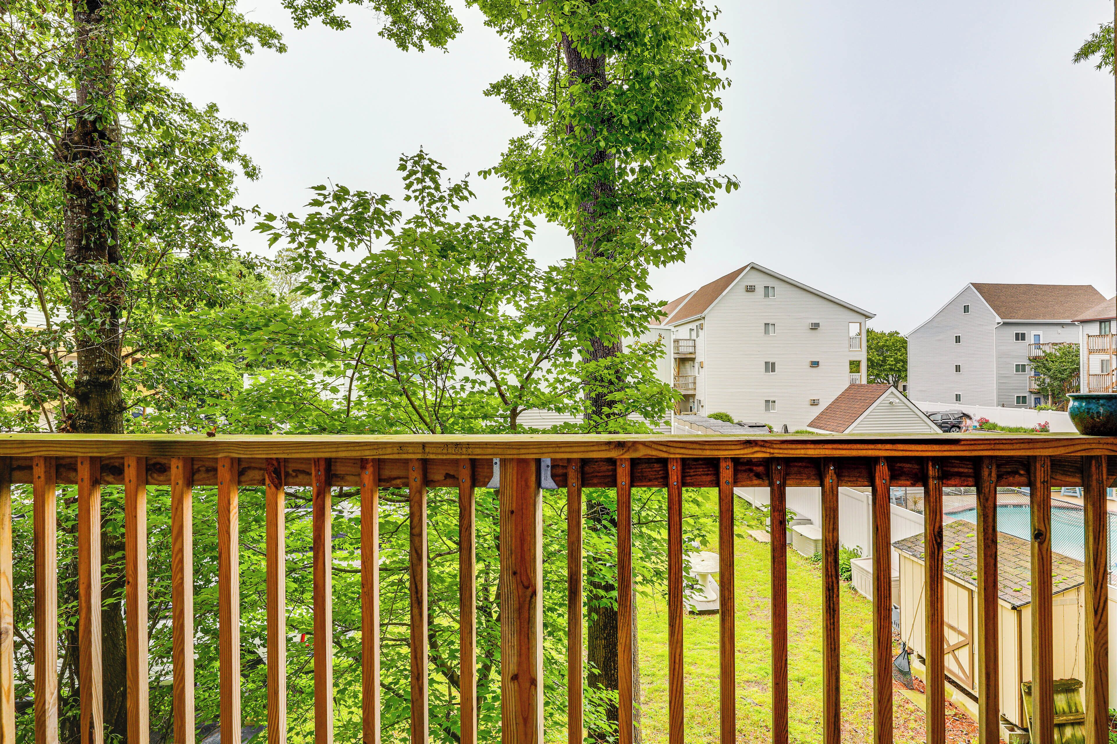 A residential area with a wooden deck, a swimming pool, and houses in the background.