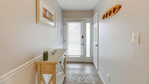A hallway with a wooden bench, a framed picture, and a surfboard decoration on the wall. - Walk to Beach + Restaurants: Ocean City Getaway (Ocean City)