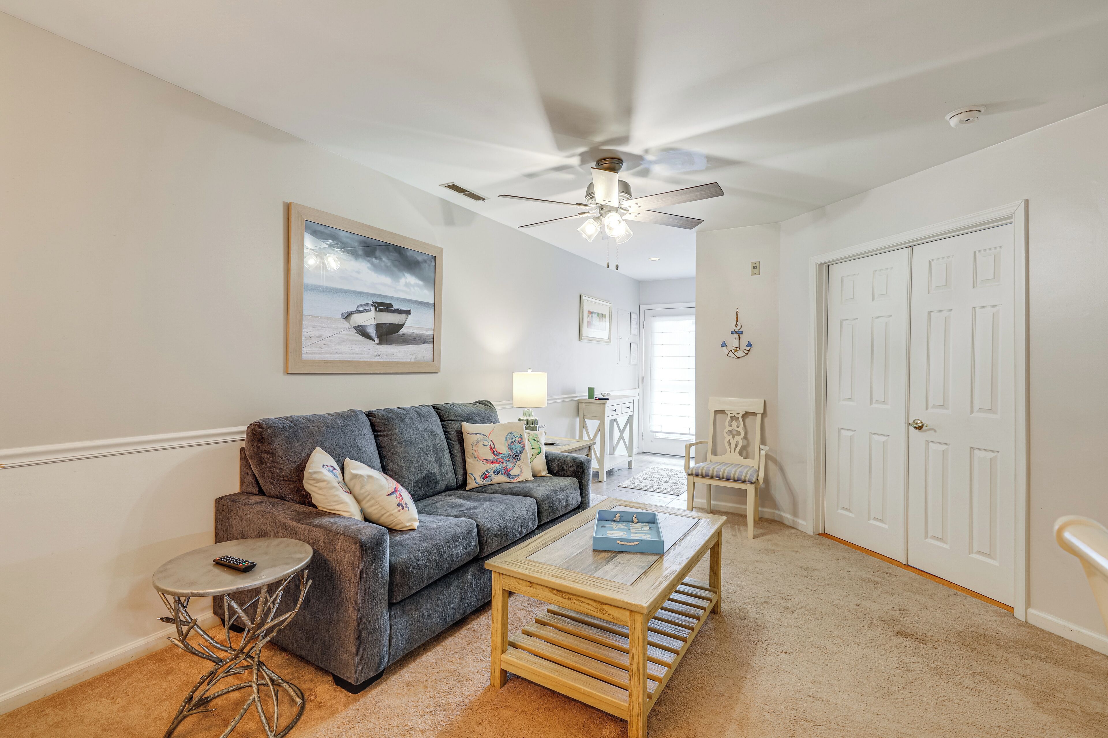 A living room with a gray sofa, a coffee table, a small side table, and a ceiling fan.